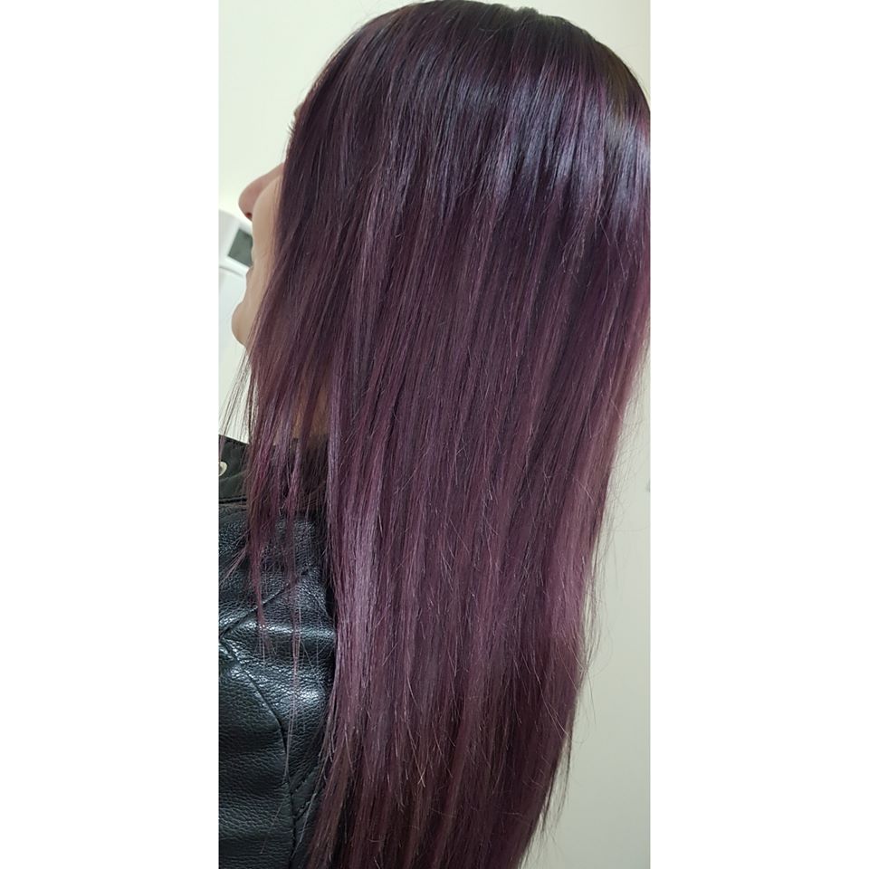 Długie, proste włosy w odcieniu ciemnej śliwki, widoczne z profilu, na tle jasnej ściany i czarnej skórzanej kurtki.