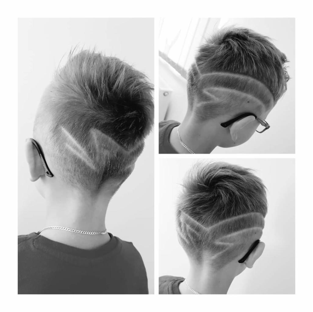 Czarno-białe ujęcie potrójne: tył głowy chłopca z wygolonym wzorem w kształcie litery V na krótkich włosach, widoczne srebrny łańcuszek i czarne okulary na uchu.