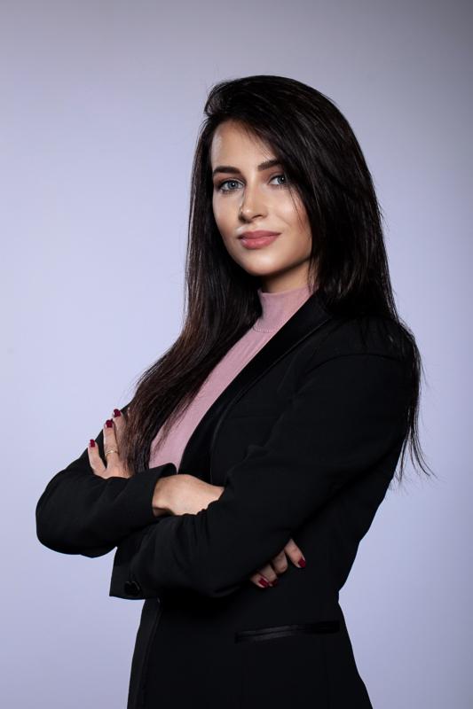 Portret kobiety w czarnej marynarce z założonymi rękami, na jasnym tle. Profesjonalny wizerunek, idealny do profilu zawodowego copywritera.