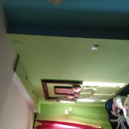 Pomalowany sufit w odcieniach zieleni i błękitu, z dekoracyjnym podwieszanym elementem i oświetleniem punktowym, widoczne fragmenty umeblowania i dekoracji wnętrza.