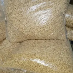 Przezroczyste worki foliowe wypełnione jasnymi, cylindrycznymi granulkami biopaliwa na bazie biomasy, ułożone jeden na drugim.