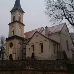 Kościół z wieżą i czerwonym dachem, częściowo ośnieżonym, na tle pochmurnego nieba, z widocznymi rusztowaniami przy wieży.