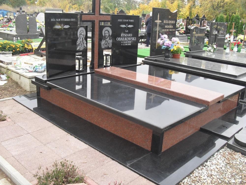 Częściowo polerowany, czarny granitowy nagrobek z elementami z czerwonego granitu, z wyrytymi wizerunkami religijnymi i inskrypcjami, ustawiony na cmentarzu z innymi nagrobkami w tle.