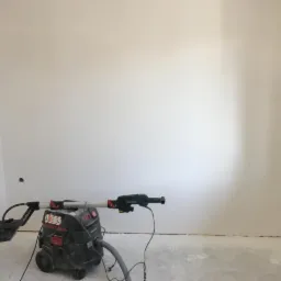 Pokój po szlifowaniu ścian, widoczny sprzęt Metabo do szlifowania bezpyłowego, ściany przygotowane do malowania, widoczne ślady po szlifowaniu na podłodze.