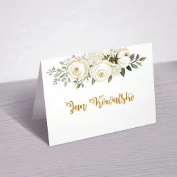 Elegancki, składany wizytownik z białym tłem, zdobiony akwarelowymi białymi r&oacute;żami i złotym napisem 'Jan Kowalski', leżący na szarej, drewnianej powierzchni z delikatnym cieniem w tle.