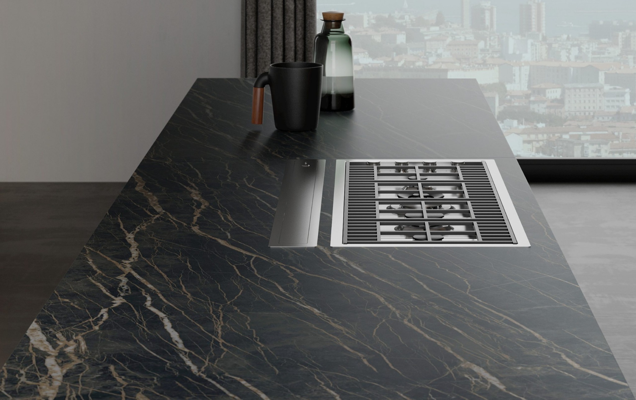 Czarny blat kuchenny z marmurowym wzorem, wbudowana płyta grzewcza, kubek i butelka na tle okna z widokiem na miasto.
