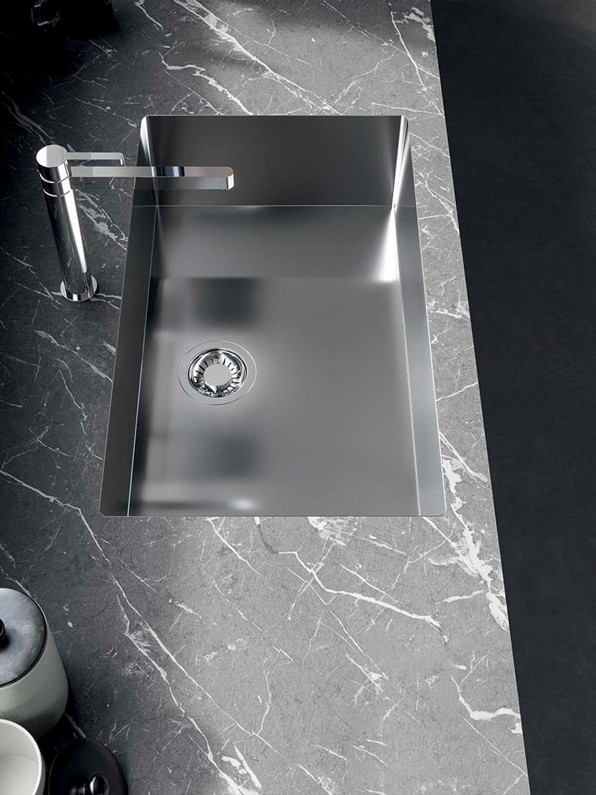 Nowoczesny, prostokątny zlew ze stali nierdzewnej z chromowaną baterią, wkomponowany w blat z szarego marmuru z białymi żyłami, widok z góry.