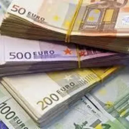 Stosy banknotów euro o różnych nominałach (50, 100, 200, 500) spięte gumkami recepturkami, ułożone na tle innych banknotów euro.