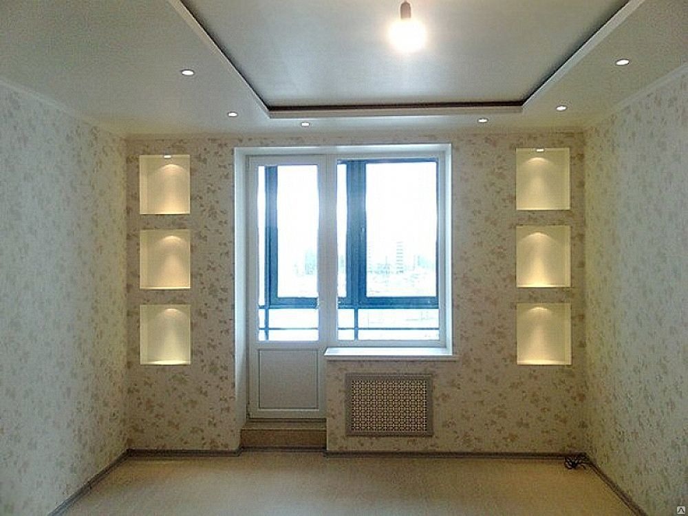 Pokój po remoncie z tapetą w drobne kwiatki, trzema podświetlanymi wnękami na ścianie po obu stronach okna balkonowego oraz podwieszanym sufitem z oświetleniem punktowym.