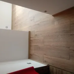 Ukończona podłoga z paneli imitujących drewno, widok z góry, fragment czerwonej wykładziny w rogu.