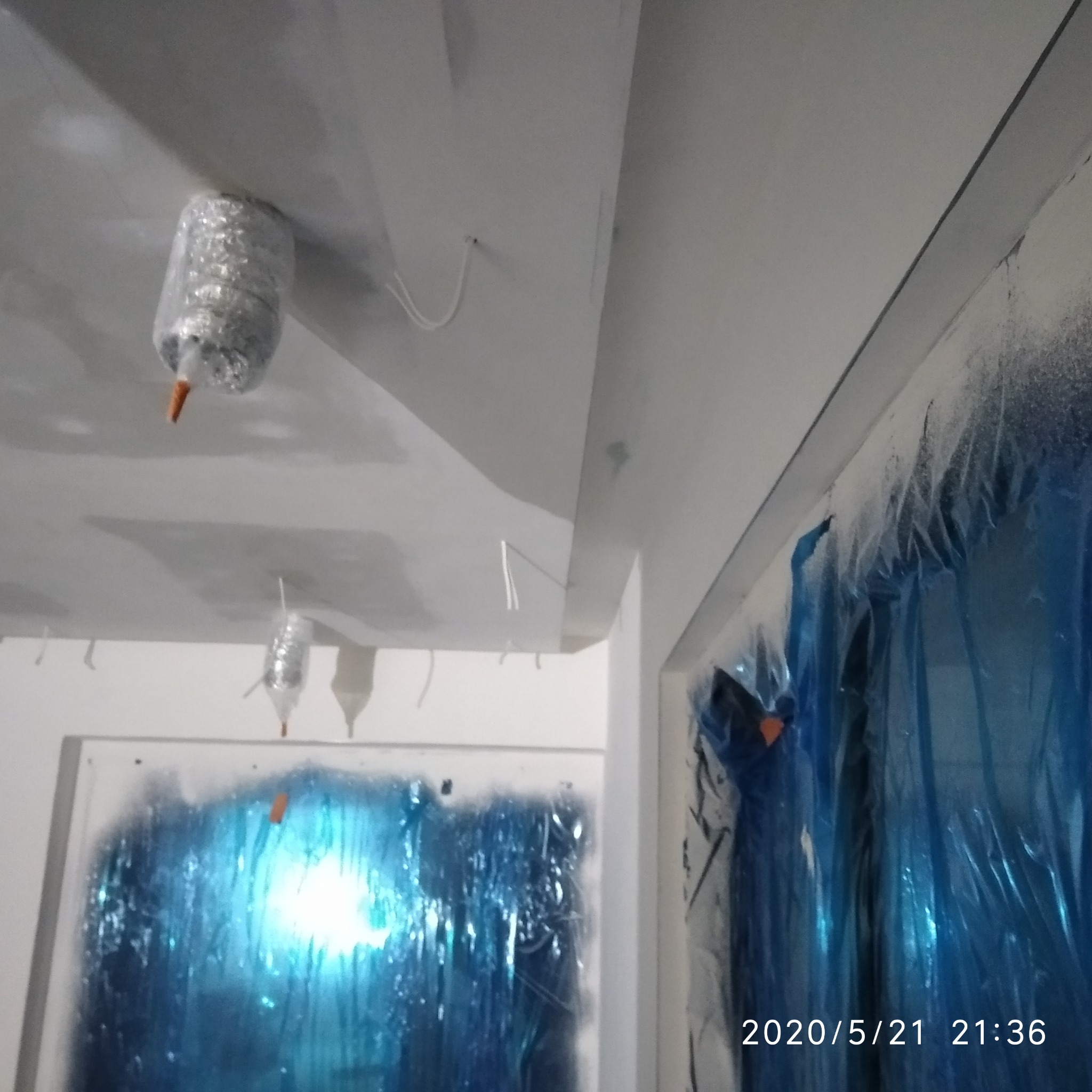 Przygotowanie do malowania sufitu: lampy zabezpieczone folią, okna osłonięte niebieską folią ochronną.