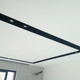 Biały sufit napinany z czarnymi, prostokątnymi wstawkami i punktowym oświetleniem LED, widoczne okno i fragment ściany w szarym kolorze.