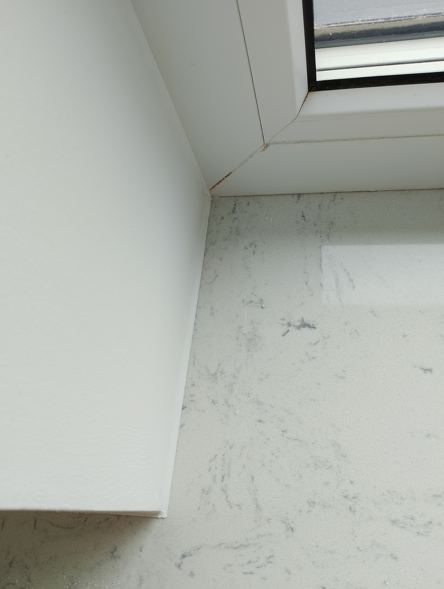 Detal narożnika okna połączonego z ścianą i blatem, widoczne drobne niedoskonałości w łączeniu elementów.