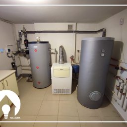 Sollab - Kotłownia z dwoma szarymi zbiornikami akumulacyjnymi ciepła marki DEMET i Vaillant, połączonymi rurami, z widoczną armaturą i osprzętem na beżowych płytkach podłogowych.