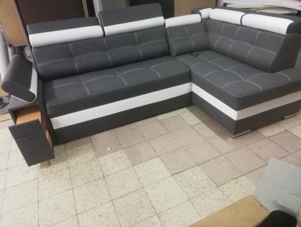 Szary narożnik z funkcją relax i barkiem, z białymi akcentami, widoczny wysuwany barek w bocznej części, na tle płytek podłogowych.