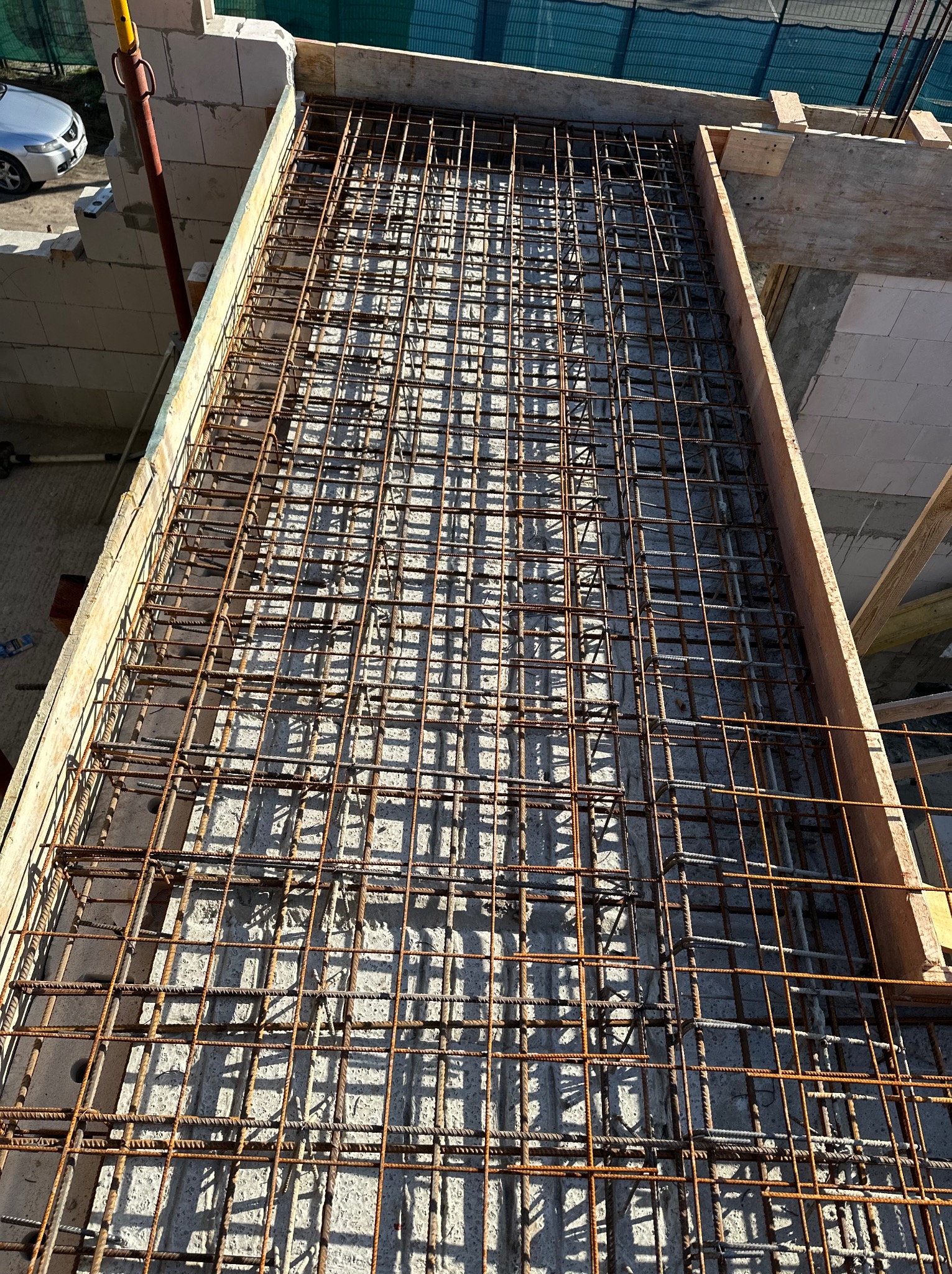 Zbrojenie stropu z siatki stalowej, przygotowane do zalania betonem, widoczne szalunki drewniane i ściany z betonu komórkowego w tle.