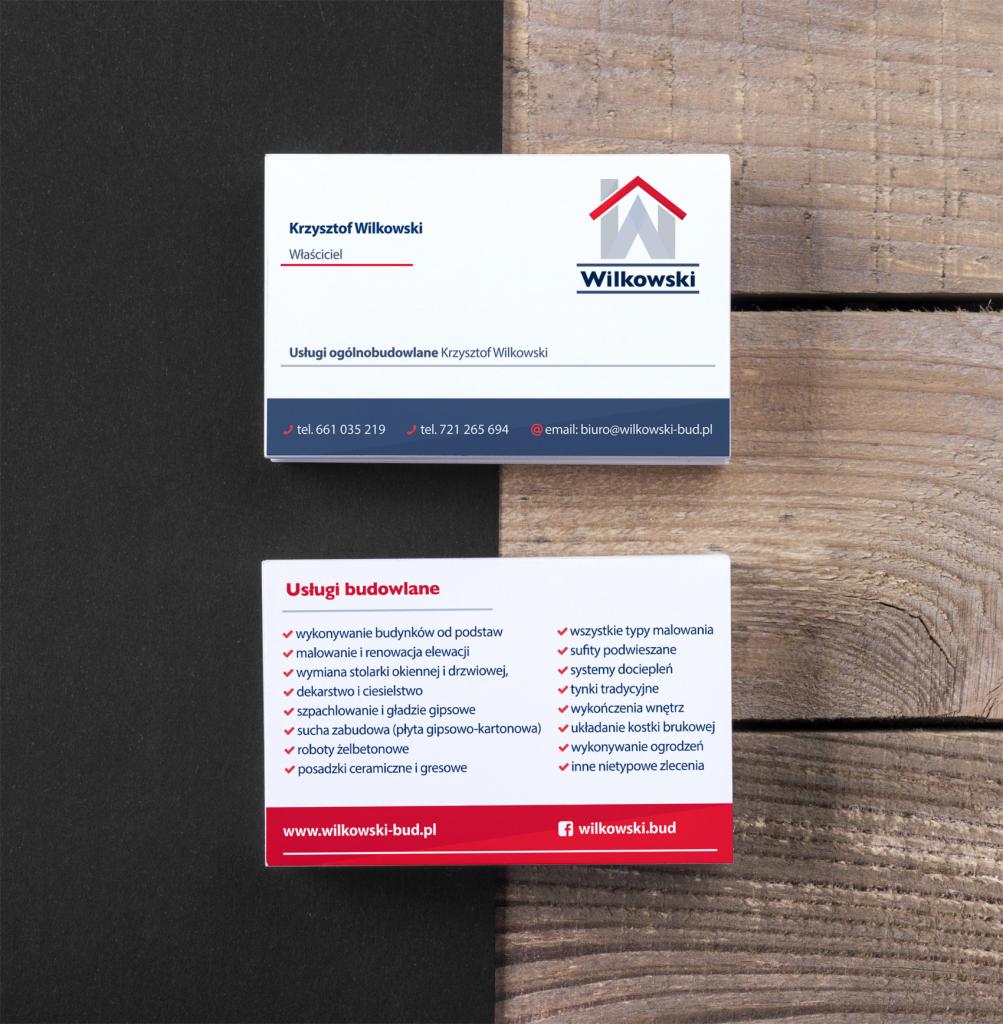 Dwie wizytówki firmy budowlanej Wilkowski na drewnianym tle, prezentujące dane kontaktowe, logo i zakres usług budowlanych.