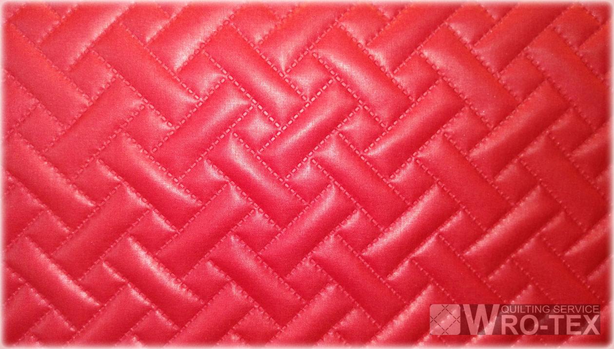 Czerwona, pikowana tkanina z wzorem w jodełkę, widoczne precyzyjne szwy, w prawym dolnym rogu logo firmy WRO-TEX.