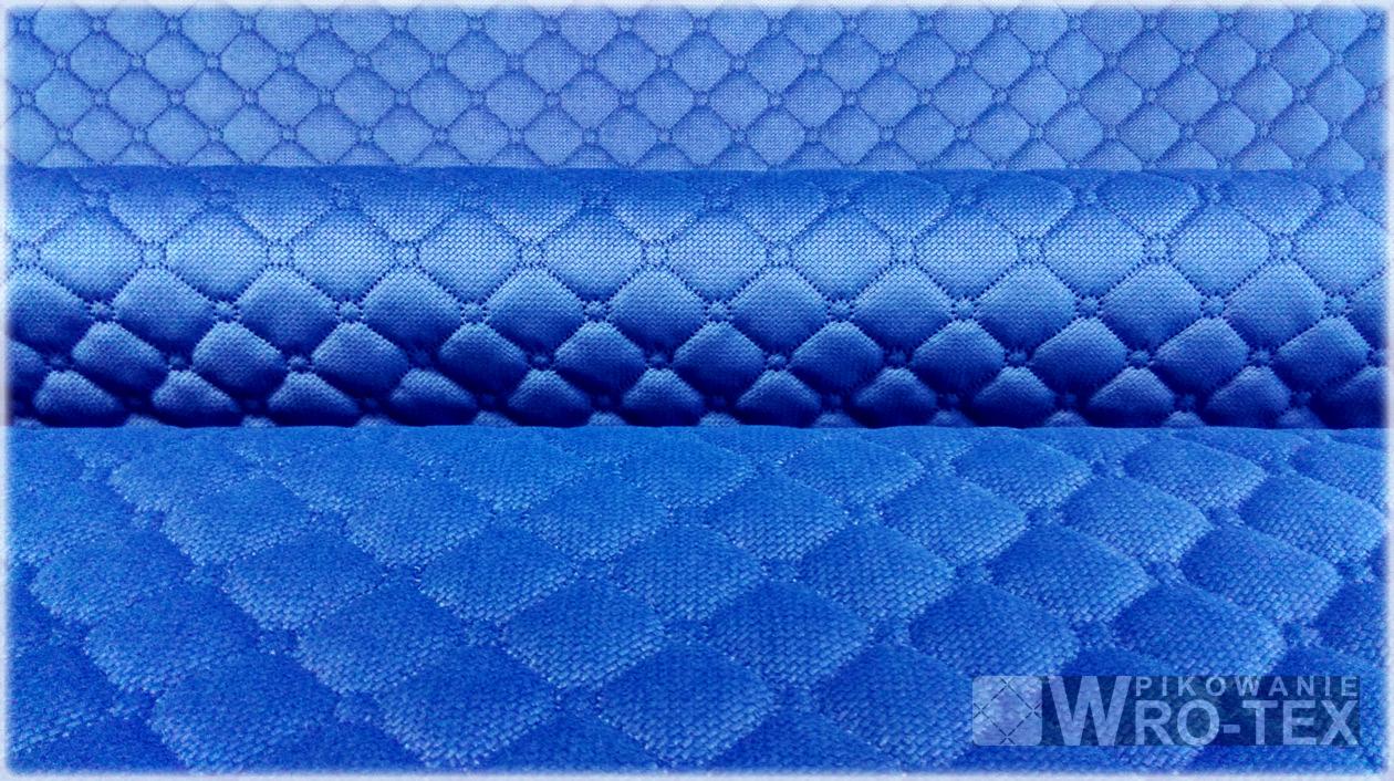 Niebieska, pikowana tkanina z wzorem rombów, ułożona w trzech warstwach, z widocznym logo producenta w prawym dolnym rogu.