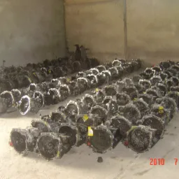 Magazyn używanych skrzyń biegów samochodowych, ułożonych rzędami na betonowej podłodze, widoczne żółte etykiety cenowe na niektórych egzemplarzach, data na zdjęciu 2010-07-20.