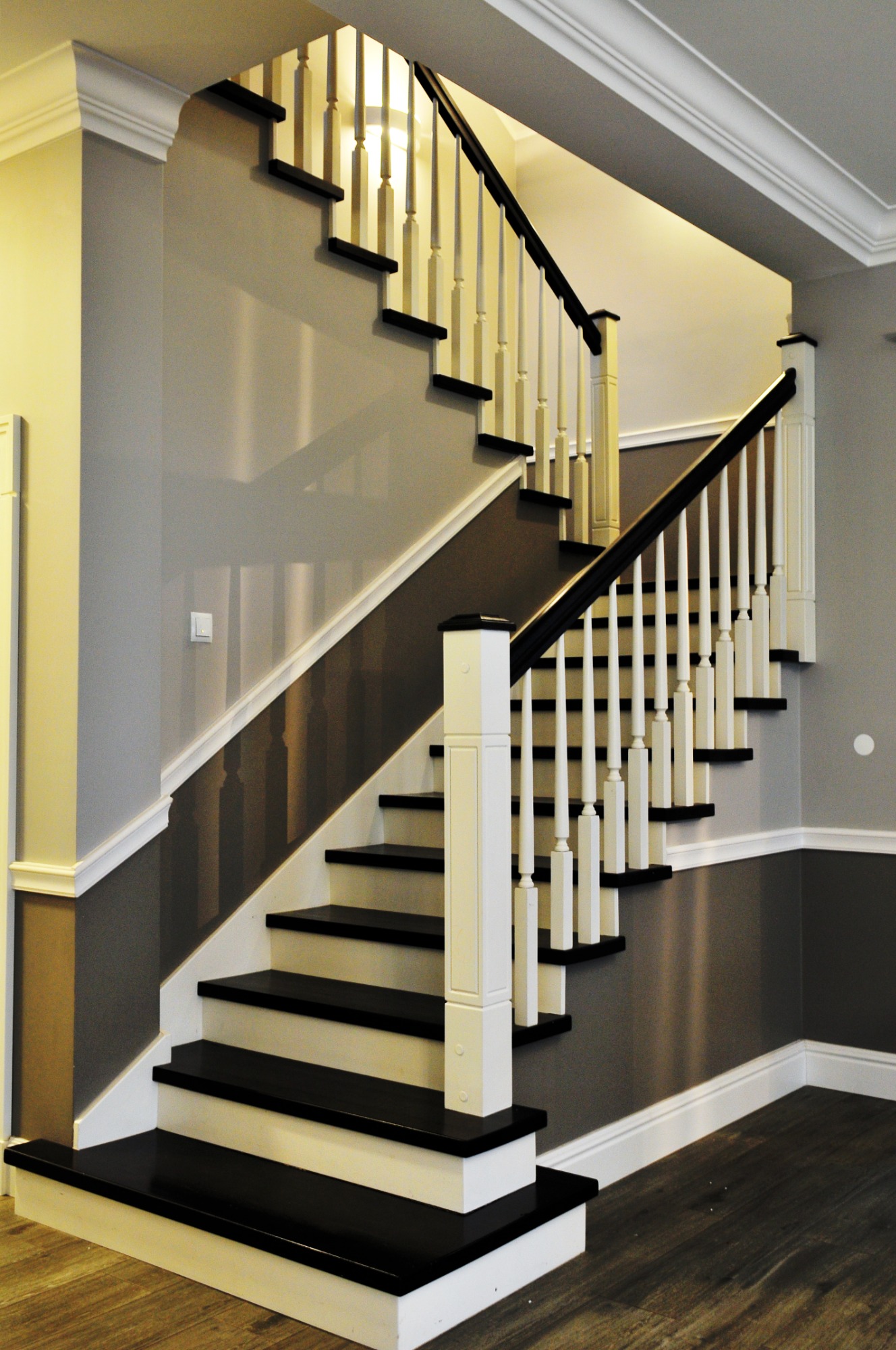 Eleganckie schody z czarnymi stopniami i białymi balustradami w domu w Wierzchowie, wykończone listwami przypodłogowymi i sztukaterią.
