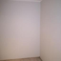 FHU Dariusz Bojaś - Pomalowany na szaro róg pokoju z listwą przypodłogową i wykończeniową, widoczne panele podłogowe imitujące drewno.