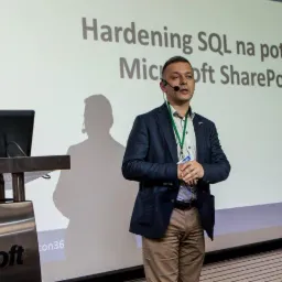 Prelegent Marcin Pytlik z mikrofonem prezentuje temat 'Hardening SQL na potrzeby Microsoft SharePoint' podczas konferencji w Milewie, widoczny laptop na mównicy.