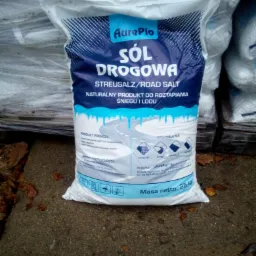 Worek 25 kg soli drogowej marki AurePio, przeznaczonej do roztapiania śniegu i lodu, stojący na betonowej powierzchni z opadłymi liśćmi.