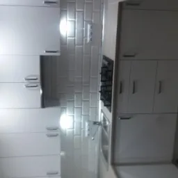 Nowoczesna, biała kuchnia z płytkami typu metro na ścianie, drewnopodobną podłogą i wbudowanym oświetleniem punktowym.