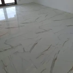 Białe, błyszczące płytki podłogowe z marmurkowym wzorem w nowym, pustym pokoju z oknem.