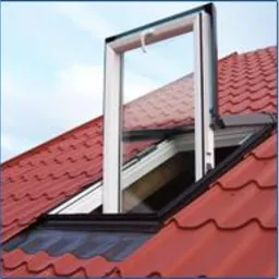 Otwarty okno dachowe PCV Skylight Premium z białym profilem i kołnierzem, zamontowane w czerwonym dachu z dachówki ceramicznej, widoczne z perspektywy lekko od dołu na tle błękitnego nieba.