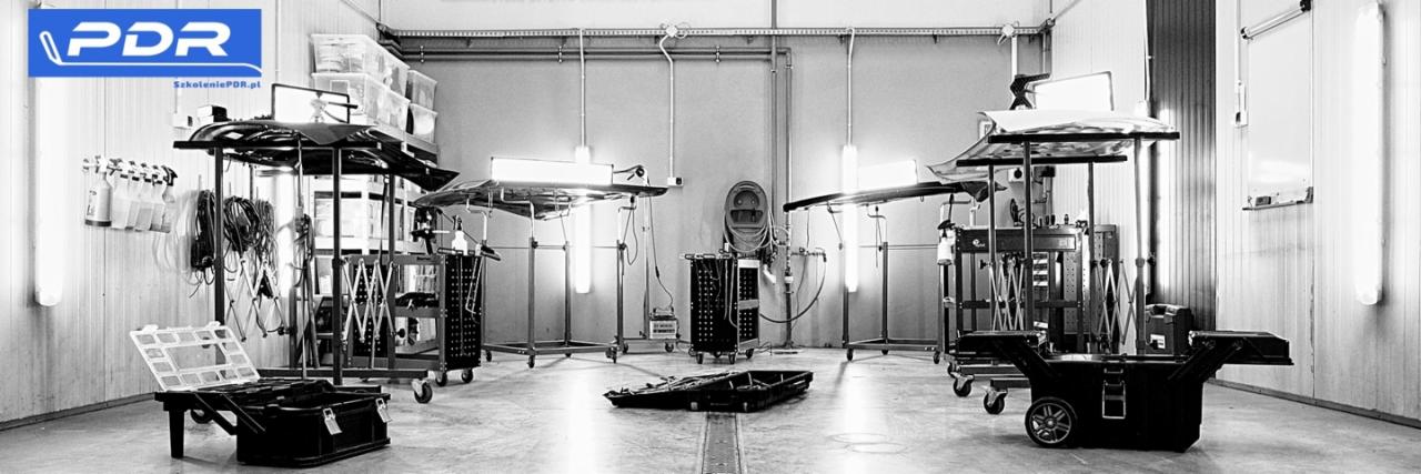Warsztat PDR w monochromatycznej tonacji: stanowiska pracy z lampami i narzędziami do bezlakierowego usuwania wgnieceń, logo PDR w lewym górnym rogu.