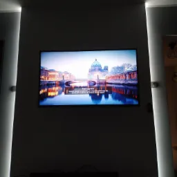 Telewizor LCD na ścianie z podświetleniem LED, wyświetlający panoramę Berlina z widocznym komunikatem 'Brak sygnału'.