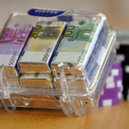 Pudełko z czekoladkami w kształcie banknotów euro (500, 200, 100) z firmy z Brzegu, na drewnianym stole, w tle żetony do pokera.