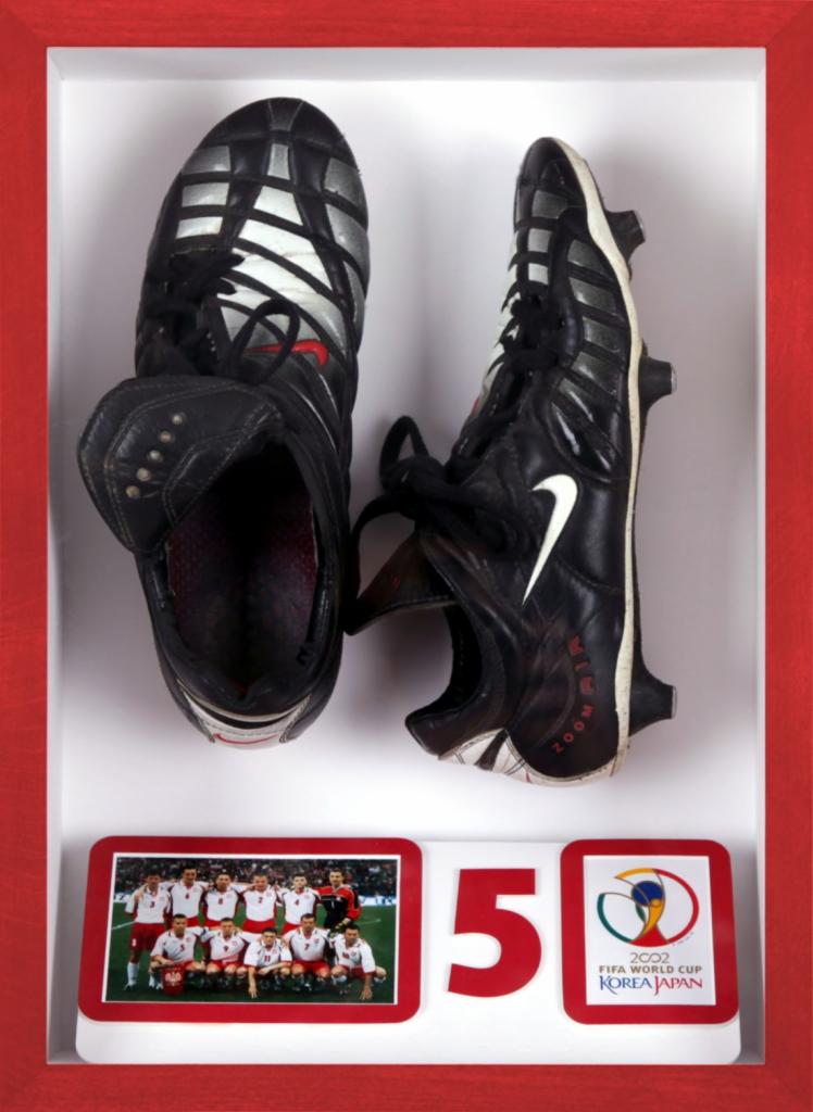 Oprawione w czerwoną ramę buty piłkarskie Nike Air Zoom, poniżej zdjęcie drużyny i logo FIFA World Cup Korea Japan 2002, numer 5.
