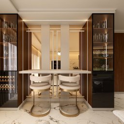 TULLAHOME Sp. z o.o. - Elegancki barek z szafkami na wino i kieliszki, oświetlony LED, z dwoma krzesłami barowymi na marmurowej podłodze. Widok na kuchnię w tle.