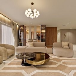 TULLAHOME Sp. z o.o. - Elegancki salon z beżowymi sofami, okrągłym stolikiem kawowym z elementami złota i marmurową podłogą. W tle przeszklone witryny i jadalnia.