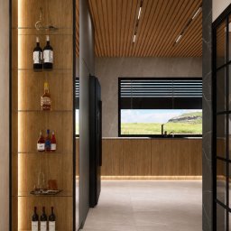 TULLAHOME Sp. z o.o. - Nowoczesna kuchnia z drewnianą zabudową, oświetloną półką na alkohole i widokiem na zielony krajobraz za oknem. Minimalistyczny design z elementami naturalnymi.