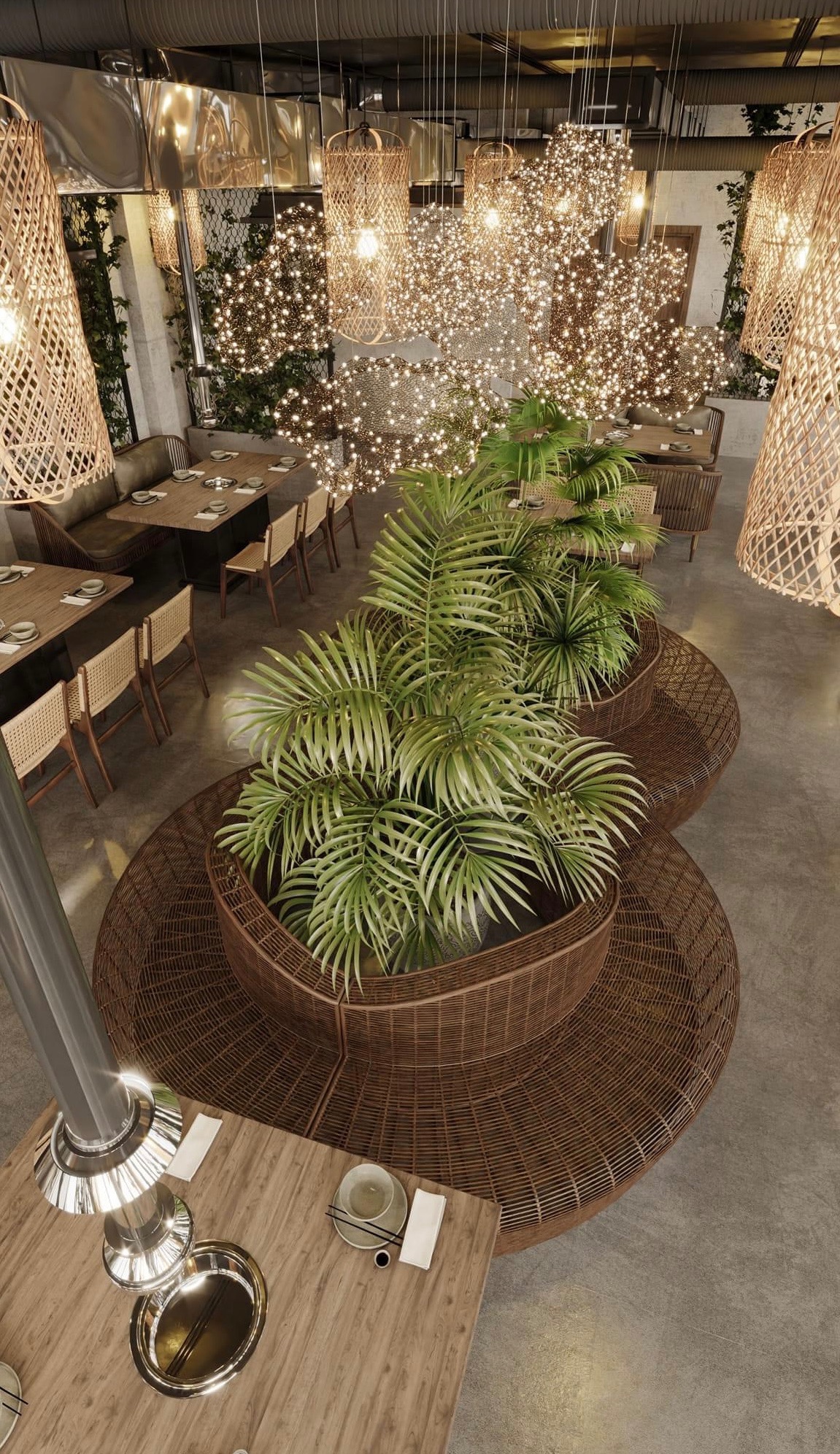 Wnętrze restauracji z dekoracyjnym oświetleniem i roślinami w plecionych donicach, widok z góry na stoły z zastawą i krzesłami z plecionymi oparciami.