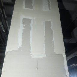 Mariusz Kujawski M-BUD - Płyta gipsowa z nałożoną warstwą szpachli w czterech miejscach, widok z dołu, surowe wykończenie, oświetlenie budowlane.