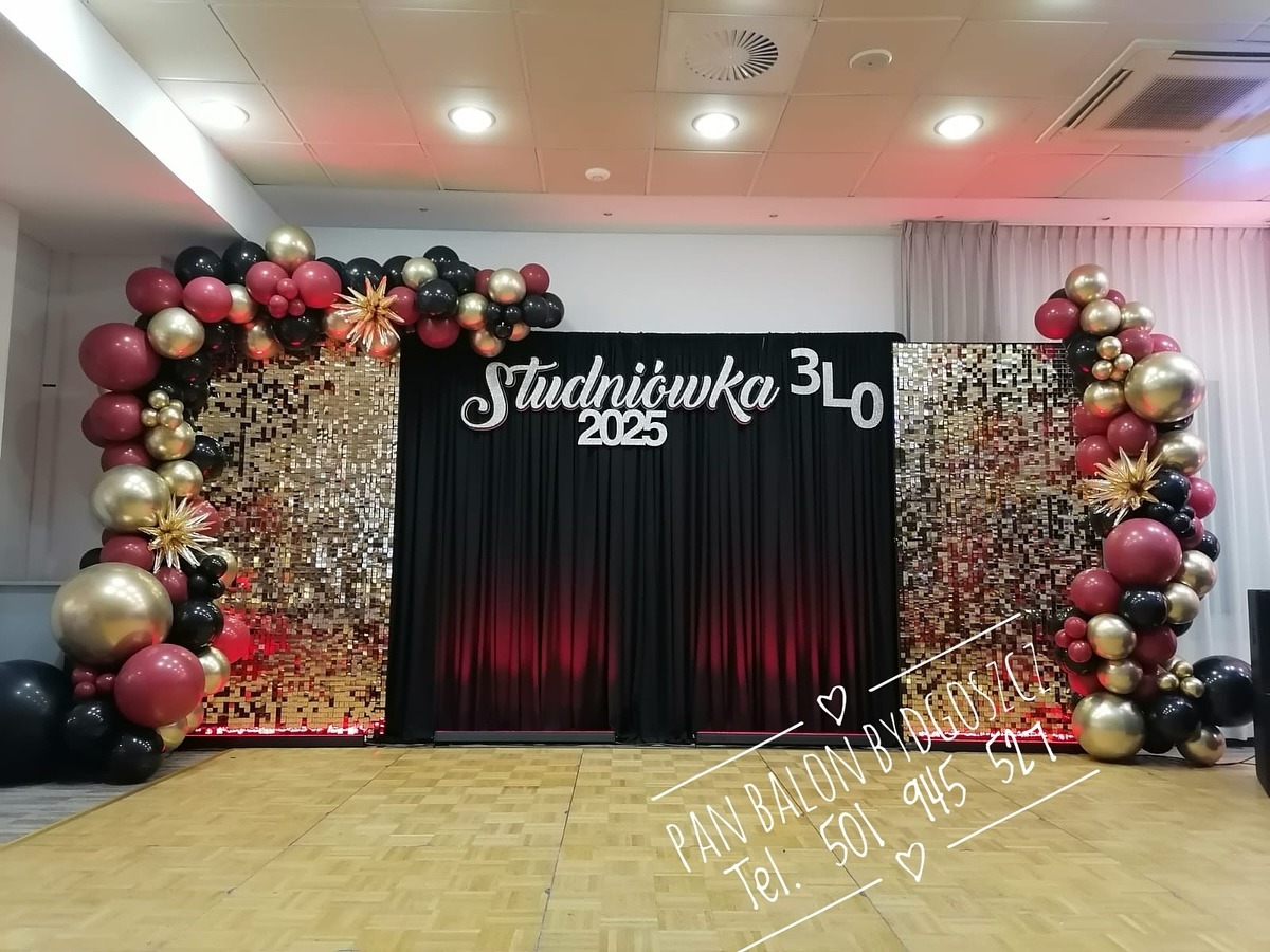 Dekoracja sali na studniówkę 3LO 2025 z czarnym tłem, złotymi cekinami i girlandami z czarnych, złotych i bordowych balonów. Na podłodze widoczny napis reklamowy 'PAN BALON BYDGOSZCZ'.