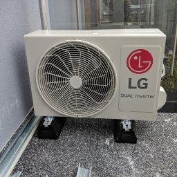 Montaż zewnętrznej jednostki LG na balkonie. Estetyczna podstawa z tworzywa bitumicznego w standardzie, dodatkowo tłumi wibracje.