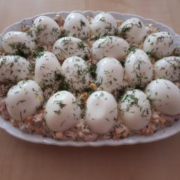 Stowarzyszenie Na Rzecz Rozwoju Gminy Gać - Owalny biały talerz z jajami w majonezie posypanymi koperkiem, ułożonymi na sałatce warzywnej.