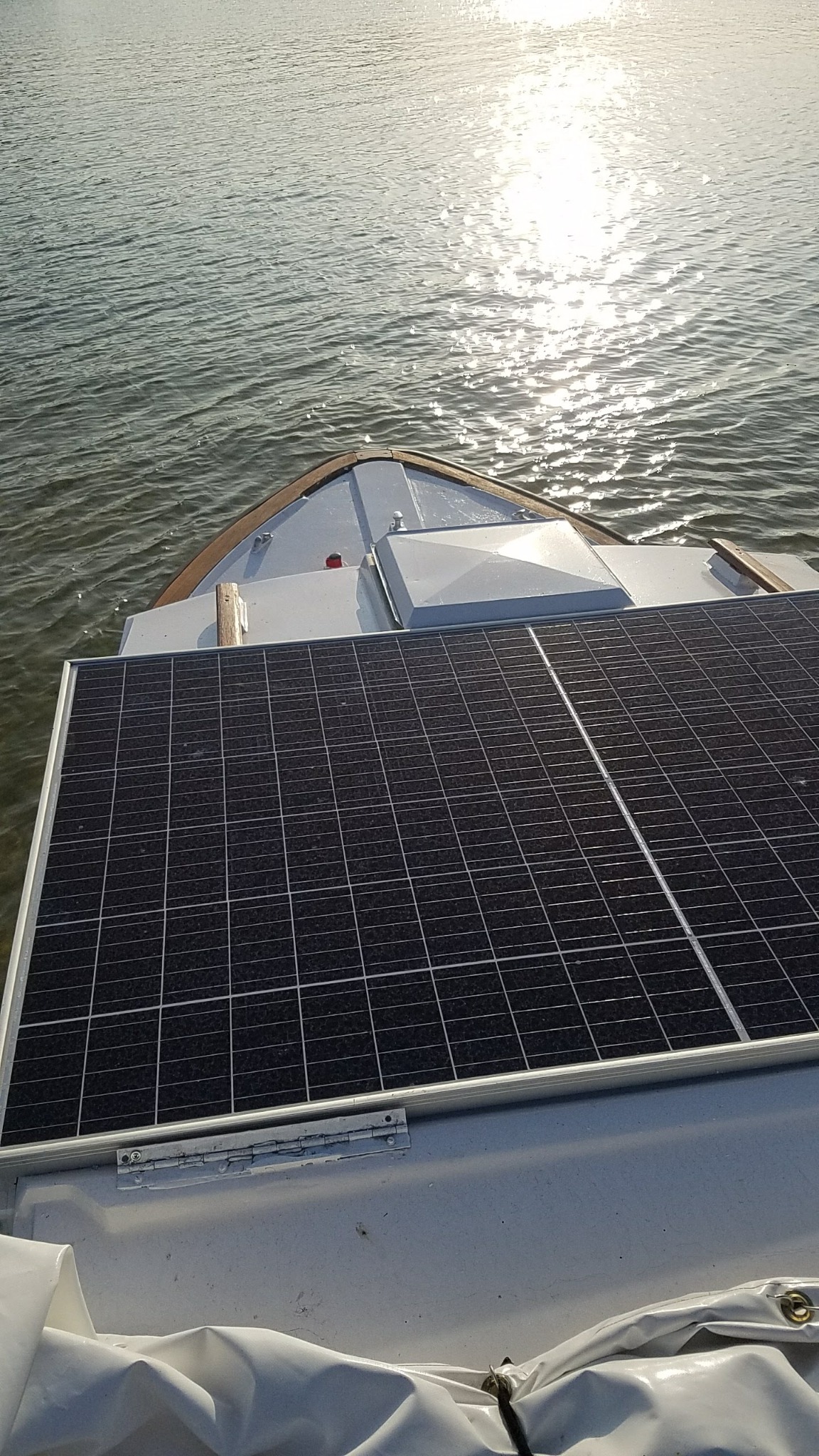 Panel słoneczny zamontowany na dachu łodzi, z widokiem na wodę odbijającą promienie słoneczne.