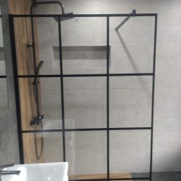 HOMME BUD Krzysiek - Kabina prysznicowa z czarnymi profilami w nowoczesnej łazience, widoczna armatura i umywalka.