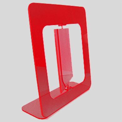 Czerwony, przezroczysty stojak z pleksi na ulotki lub wizytówki, z charakterystycznym wycięciem w podstawie i ramie, ustawiony pod kątem.