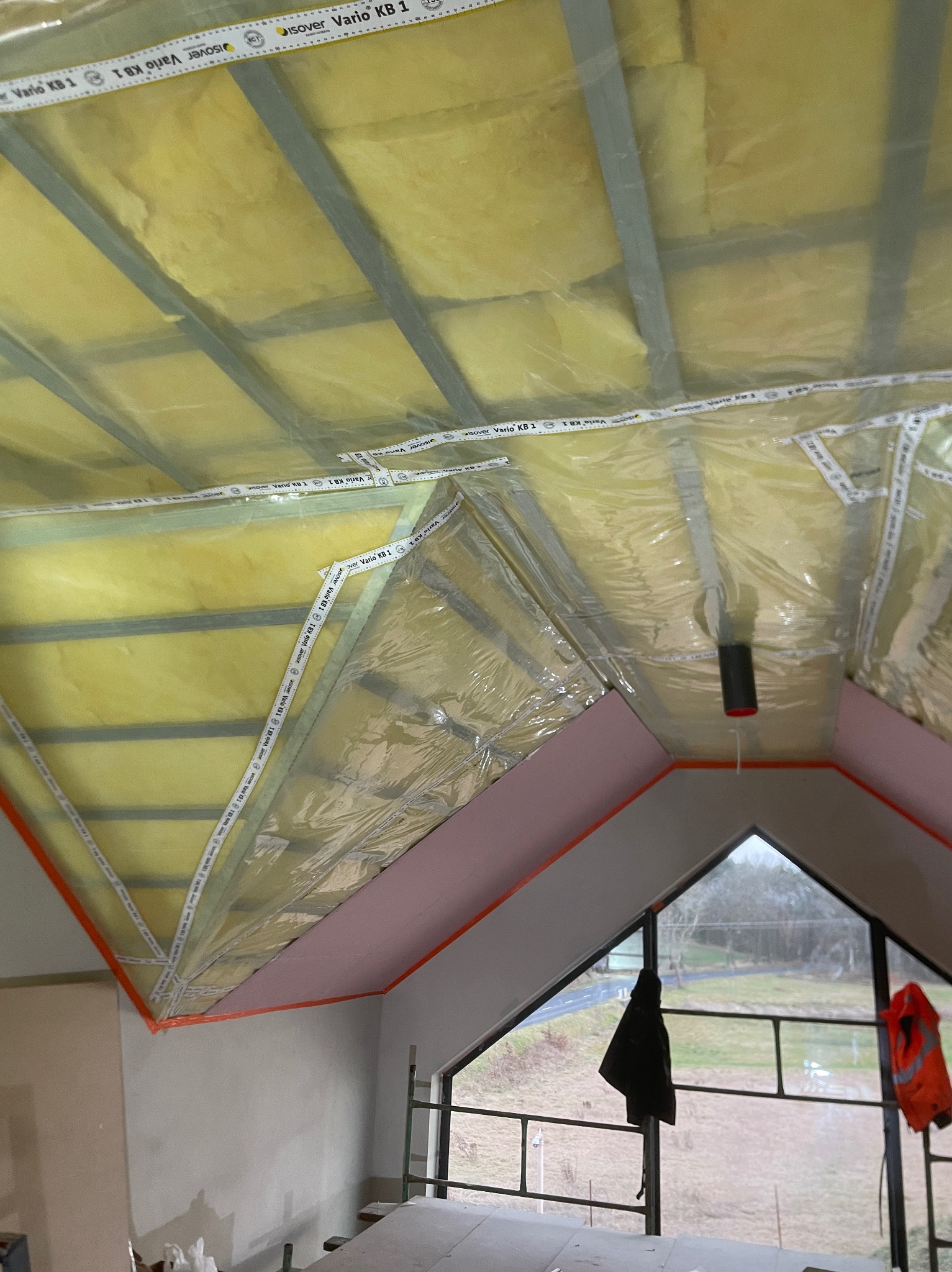 Ocieplenie poddasza wełną mineralną z folią paroizolacyjną Isover Vario KB 1, widoczne metalowe profile i fragment okna dachowego