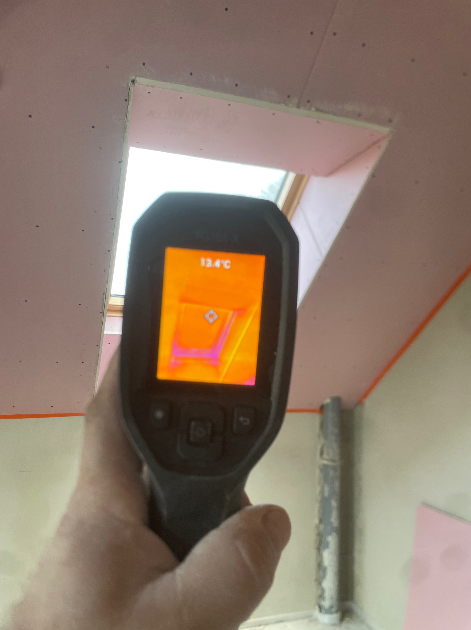 Termowizja poddasza w Nowogrodźcu, ukazująca temperaturę 13.4°C na zamontowanej płycie przy oknie dachowym, z widocznymi śladami po wkrętach.