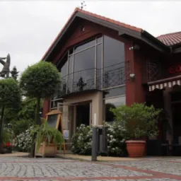 Zewnętrzny widok budynku restauracji Consonni z posągiem gimnastyka na dachu, widok z brukowanego placu