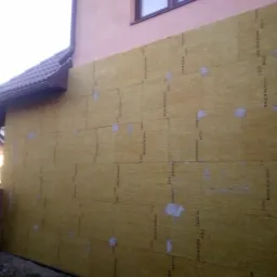 Ocieplenie ściany zewnętrznej budynku mieszkalnego wełną mineralną Rockwool Toprock, widoczne płyty przyklejone i punktowo zamocowane zaprawą klejową.
